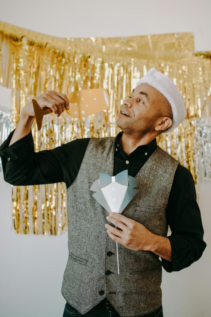 Man celebrating at a holiday party with festive decorations and props.